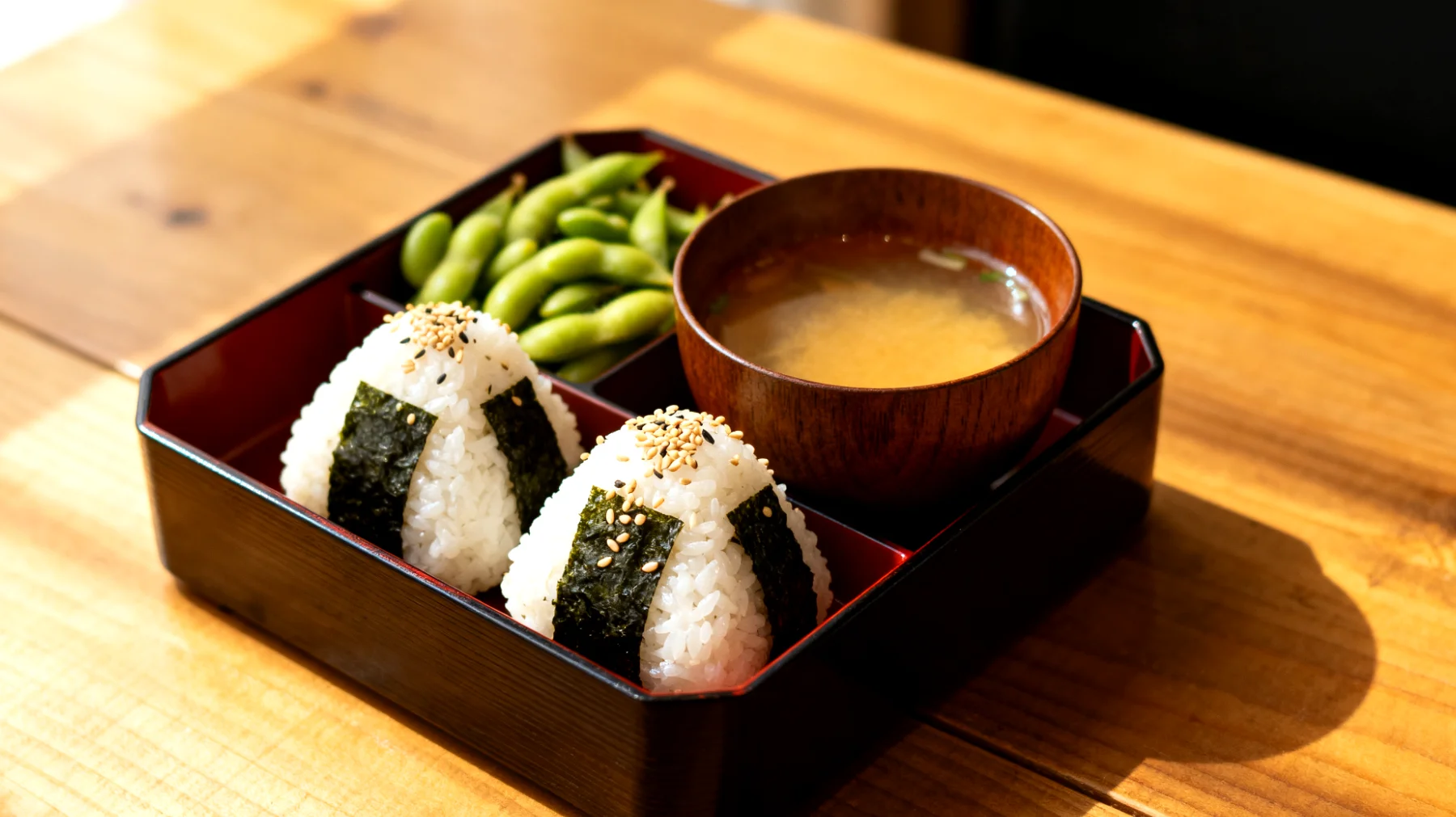 Bento-Box mit Edamame, Miso-Suppe und Onigiri (Reisbällchen mit Nori und Sesam)"